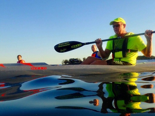 Oscar Chalupski in a surfski kayak on the water holding a paddle